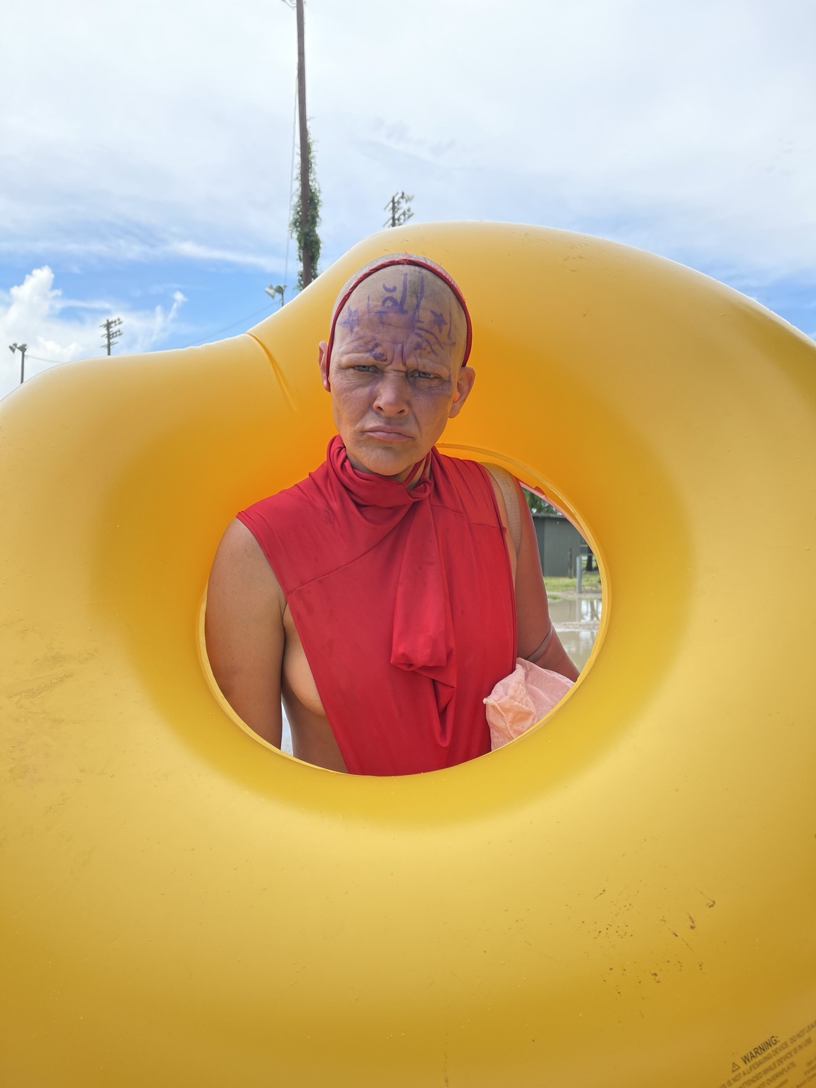 Portrait of a person in red framed by a yellow sculptural opening